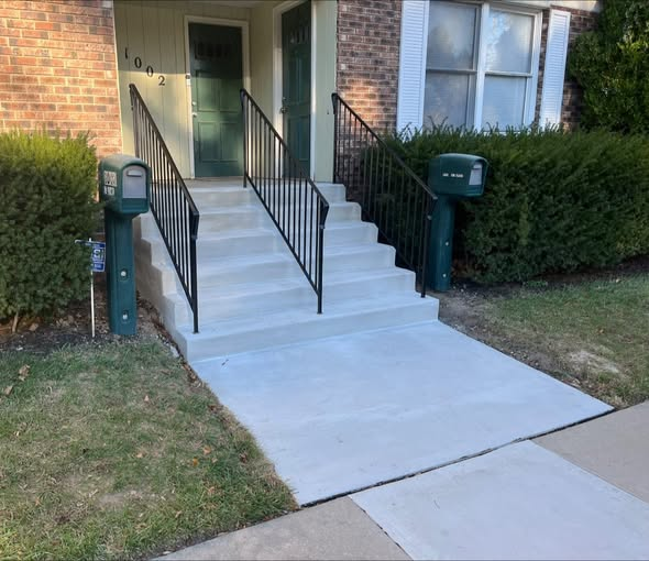 The same front entrance after replacement with new concrete steps, a new front slab, and new handrails